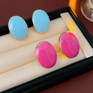 Detail of vintage oval earrings in light blue and bright pink with golden metal frames