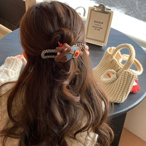 Detail of cute plush bear hair clip with denim fabric details worn on wavy hair