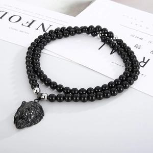 Close-up of a double-layer black bead necklace with a detailed metal lion head pendant