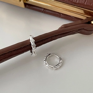 Macro view of S925 sterling silver hoop earrings with detailed leaf texture on leather