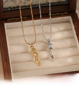 Detail of gold and silver cornicello horn pendants on bead chains inside a gift box