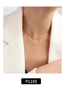 Close-up of double-layer gold snake chain necklace worn on neck over white blazer
