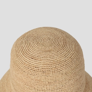 Close-up of the handcrafted spiral weave pattern on a foldable raffia bucket sun hat