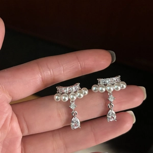 Elegant silver pearl ear clip with zircon water drop pendant held by hand