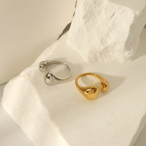 Detailed view of polished gold and silver waterdrop rings on a textured stone base
