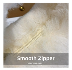 Close-up of smooth nylon zipper on plush cream faux fur bag with leather detail