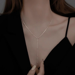 Minimalist Y-shaped necklace with gold-plated geometric tassels and round beads on model