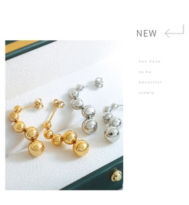 Detailed view of polished gold and silver spherical bead drop earrings on jewelry box