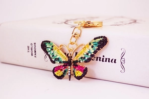 Detailed macro of a gold butterfly keychain with colorful rhinestones on a book spine