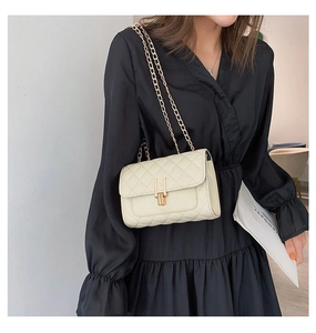 Quilted cream leather crossbody bag with gold chain strap shown on black dress model