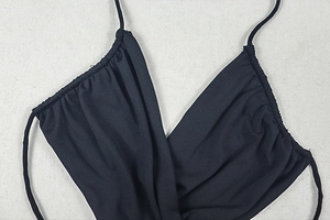 Detail of black halter dress featuring criss-cross pleated bust and slim straps