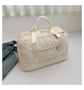Detail of off-white gym bag featuring star-embossed quilting and smooth front zipper pocket