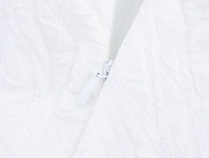 Macro view of invisible zipper and embossed texture on a white dress fabric