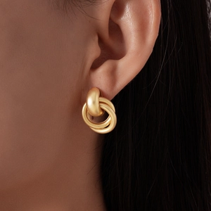 Gros plan de boucles d'oreilles géométriques dorées mates portées pour les détails