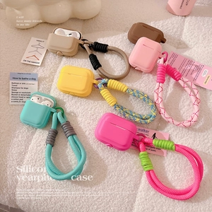 Colorful silicone AirPods Pro cases with thick braided lanyards on soft plush background