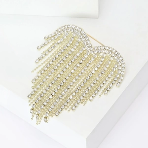 Detail of gold heart brooch with long rhinestone tassels on a geometric stand