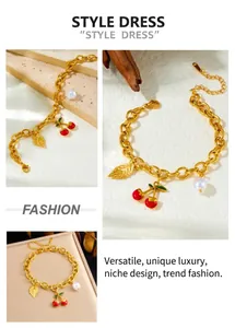 Detail of gold chunky chain bracelet with cherry, leaf and pearl charms and lobster clasp
