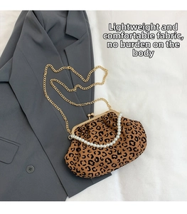 Close-up of shell-shaped leopard print clutch bag with pearl handle on a grey blazer