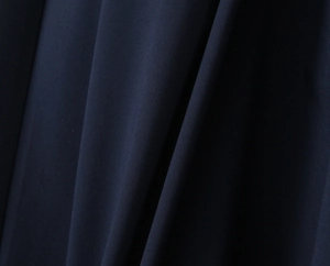 Dettaglio della trama del tessuto blu navy e del drappeggio dell'abito lungo a fascia