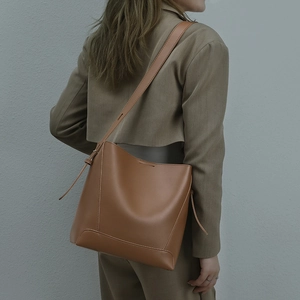 Brown leather bucket bag with adjustable strap and drawstring detail shown on model