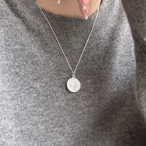 Close-up of vintage 925 silver Elizabeth coin pendant on a delicate chain necklace