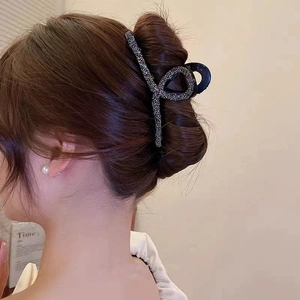 Detail of large black rhinestone hair claw clip styled in a classic bun for women
