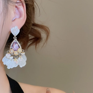 Close-up of vintage gold teardrop earring with purple crystal and matte white petals