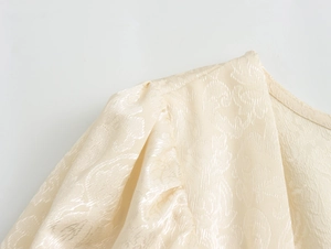 Détail du tissu jacquard beige avec volants élégants sur l'encolure carrée