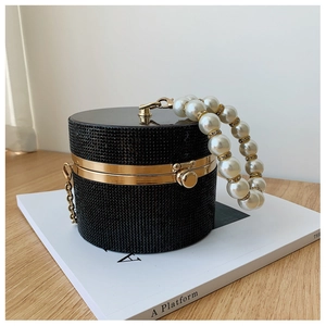 Macro shot of black cylindrical evening bag with rhinestones and pearl handle