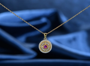 Macro shot of 925 silver gold-plated pendant with a red ruby and pavé diamonds