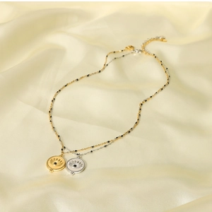 Detailed view of gold and silver evil eye necklaces on beige silk fabric background