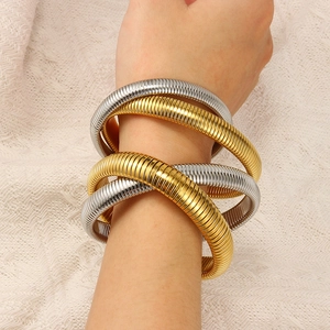 Detailed macro view of two-tone gold and silver spiral metal bracelets on a model wrist