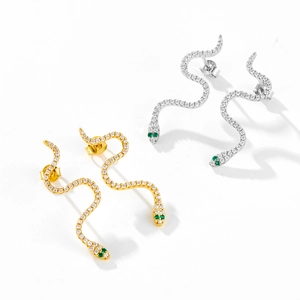 Detailed close-up of snake earrings featuring green stone eyes and micro-paved crystals