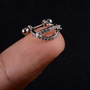 Close-up of a silver zircon-inlaid cartilage earring held by fingers for size display