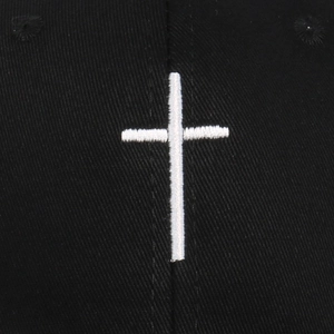 Close-up of white cross embroidery on black twill fabric of the baseball cap