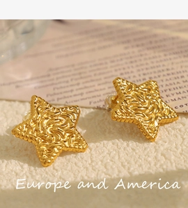 Detailed close-up of golden star earrings featuring unique wavy pleated metal texture