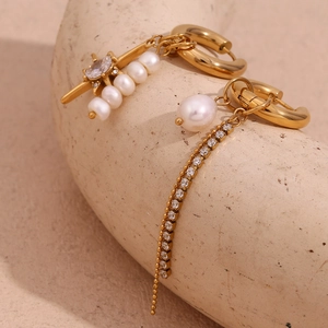 Macro view of gold star pearl asymmetric earrings with sparkling zircon chain details