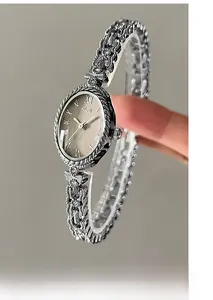 Détail du cadran ovale en nacre avec chiffres romains et bracelet en métal argenté ciselé