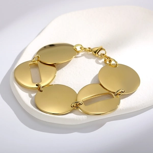 Dettaglio macro del bracciale dorato con dischi geometrici su un vassoio di ceramica