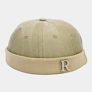 Dettaglio del logo R in metallo argento sul berretto miki in velluto a coste kaki