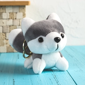 Cute gray and white plush husky keychain toy on a soft blue wooden background
