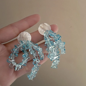Détail de boucles d'oreilles nœud avec perles de cristal bleu et texture coquillage
