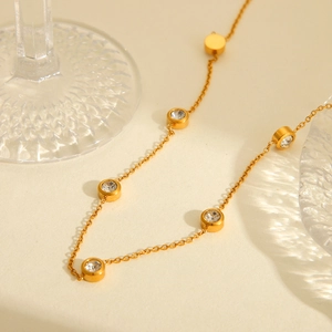 Minimalist 18K gold stainless steel necklace with circular zircon stones on beige surface