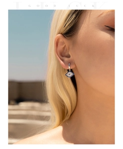 Detail of silver S925 diamond evil eye hoop earrings on blonde model with Good Luck text