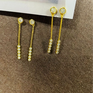 Luxueuses boucles d'oreilles pendantes dorées avec cristaux blancs sur présentoir