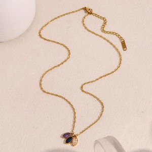Detailed view of 18K gold plated necklace featuring three teardrop zircon stones on a table