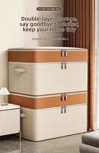 Detail of a beige foldable storage box featuring orange trim and a dual metal zipper closure