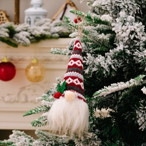Christmas gnome ornament with knitted patterned hat and white beard on a snowy pine branch