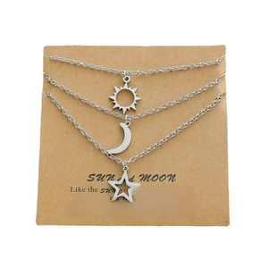 Ensemble de trois colliers en acier inoxydable avec soleil, lune et étoile sur carte