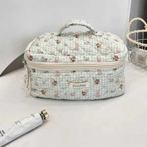 Detailed view of quilted blue checkered cosmetic bag with cute cartoon animal patterns
